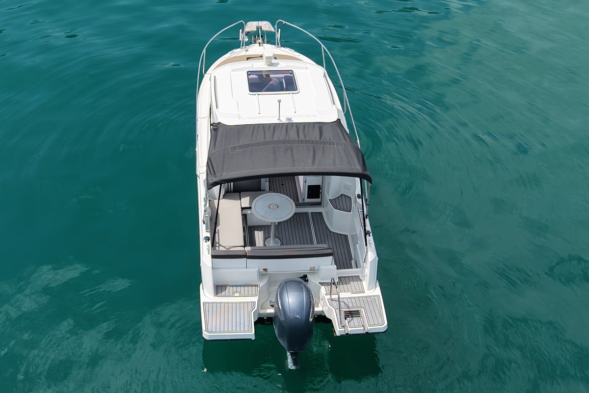 Jeanneau Merry Fisher auf dem Vierwaldstättersee: Kabinenboot von hinten mit Bimini-Sonnendach, Sitzgruppe im Cockpit und grosser Badeplattform zum Mieten ab Hergiswil bei Luzern